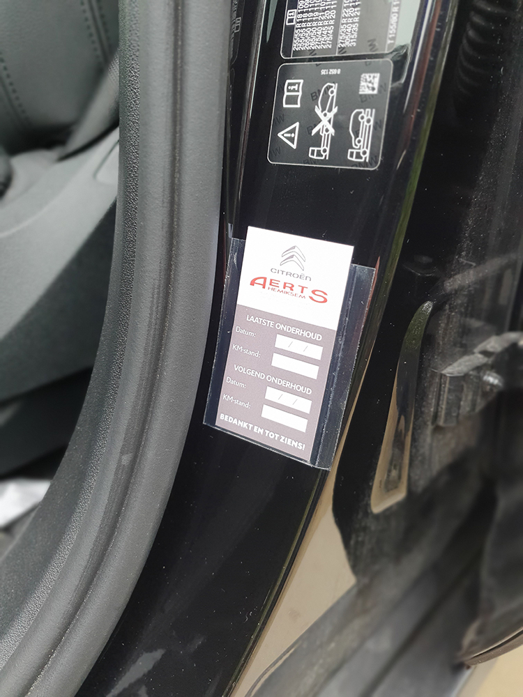 Onderhoudskaart voor auto bevestigd in deurstijl met servicegegevens