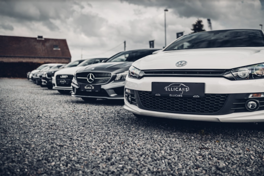 Rij wagens op grindparking met uniforme gepersonaliseerde nummerplaathouders met logo.